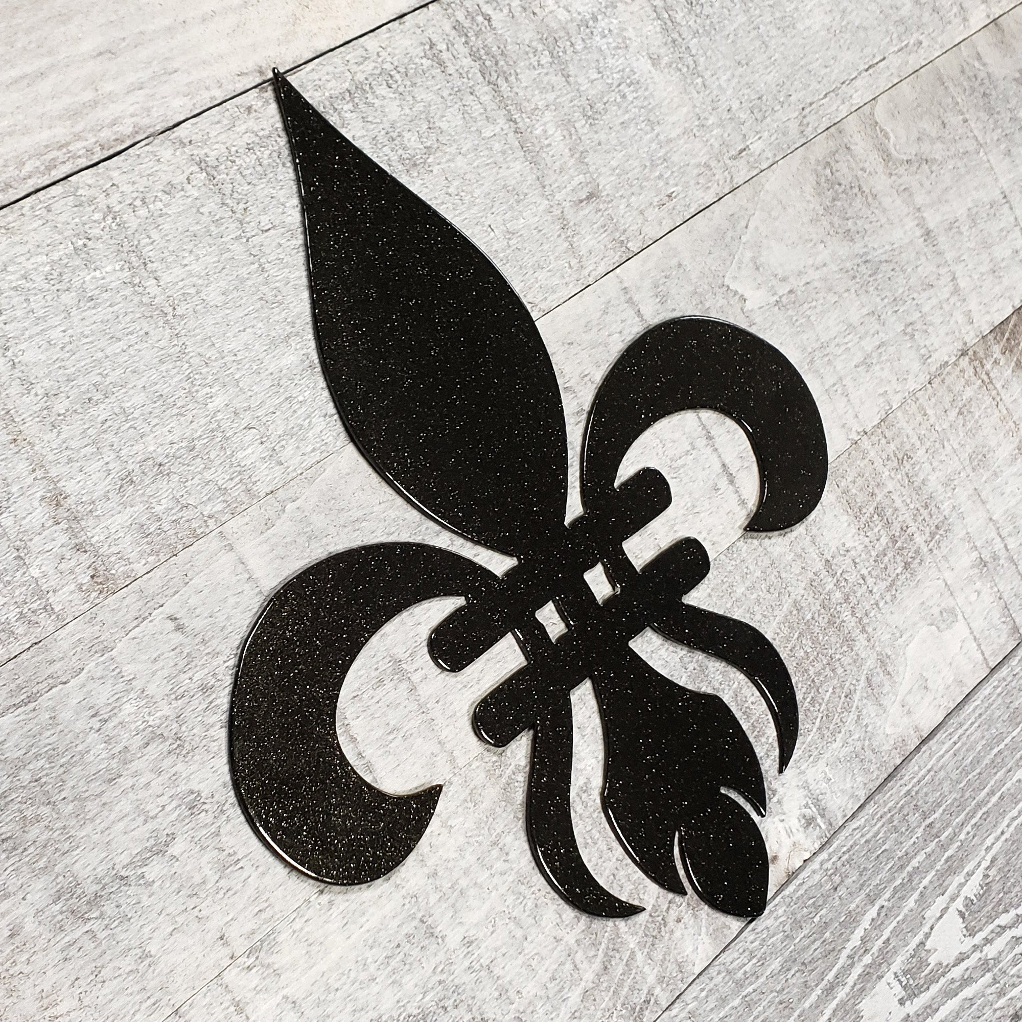 Decorative black metal fleur-de-lis on a wooden background