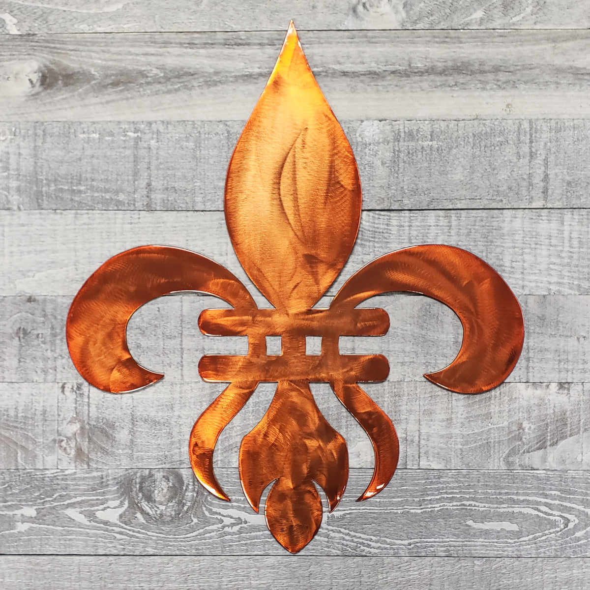 Decorative copper-colored metal fleur-de-lis on a wooden background
