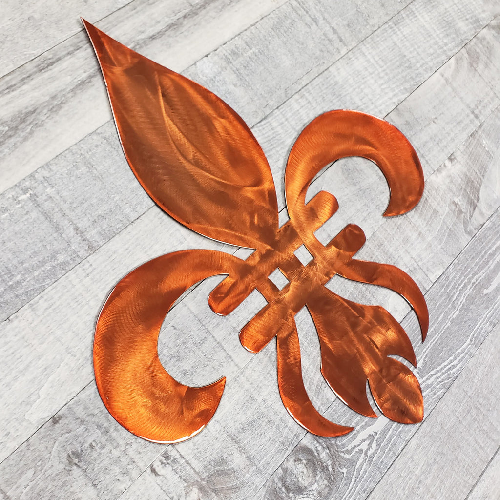Decorative copper-colored metal fleur-de-lis on a wooden background