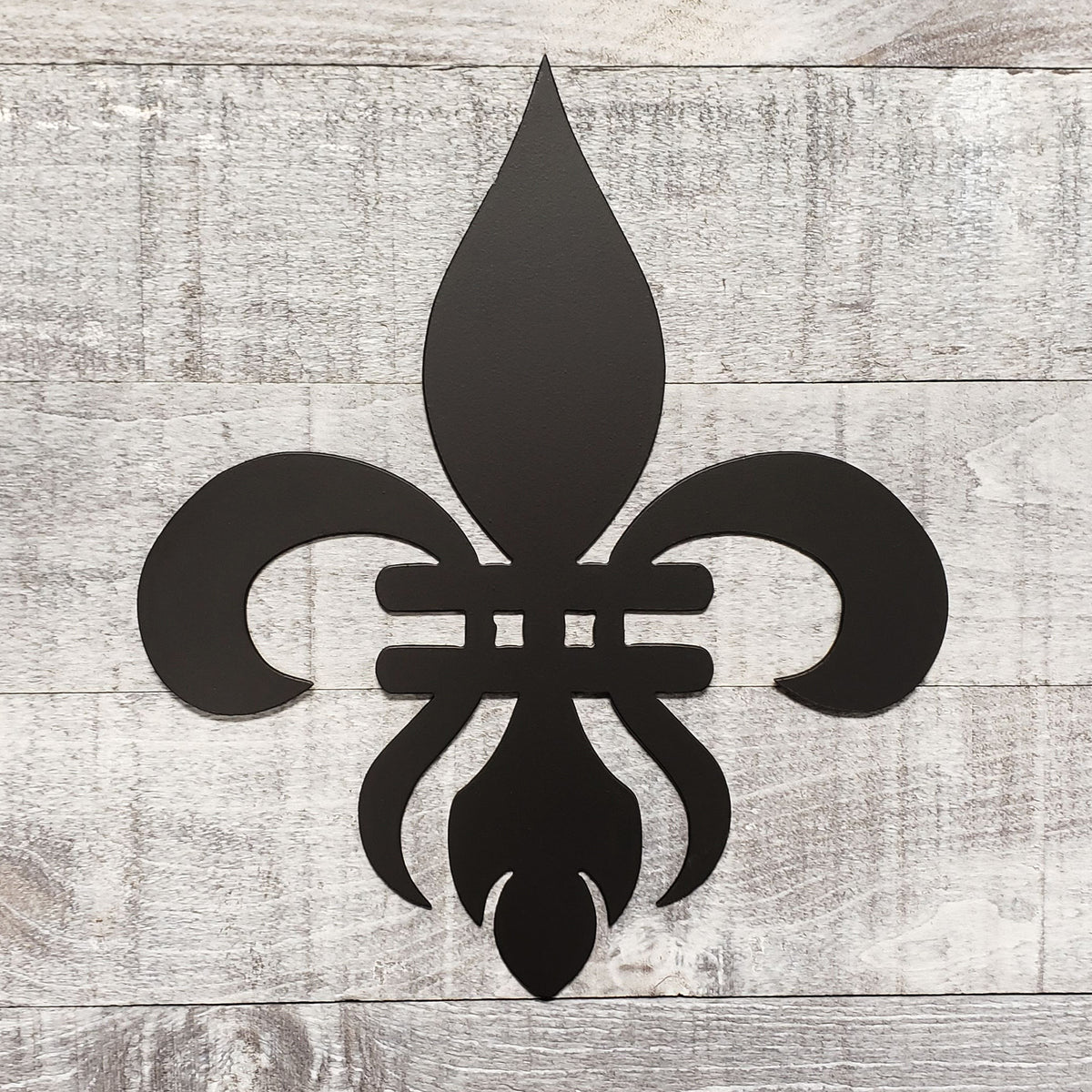 Decorative black metal fleur-de-lis on a wooden background