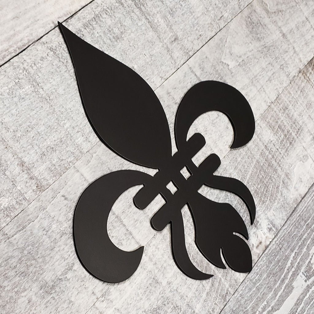 Decorative black metal fleur-de-lis on a wooden background