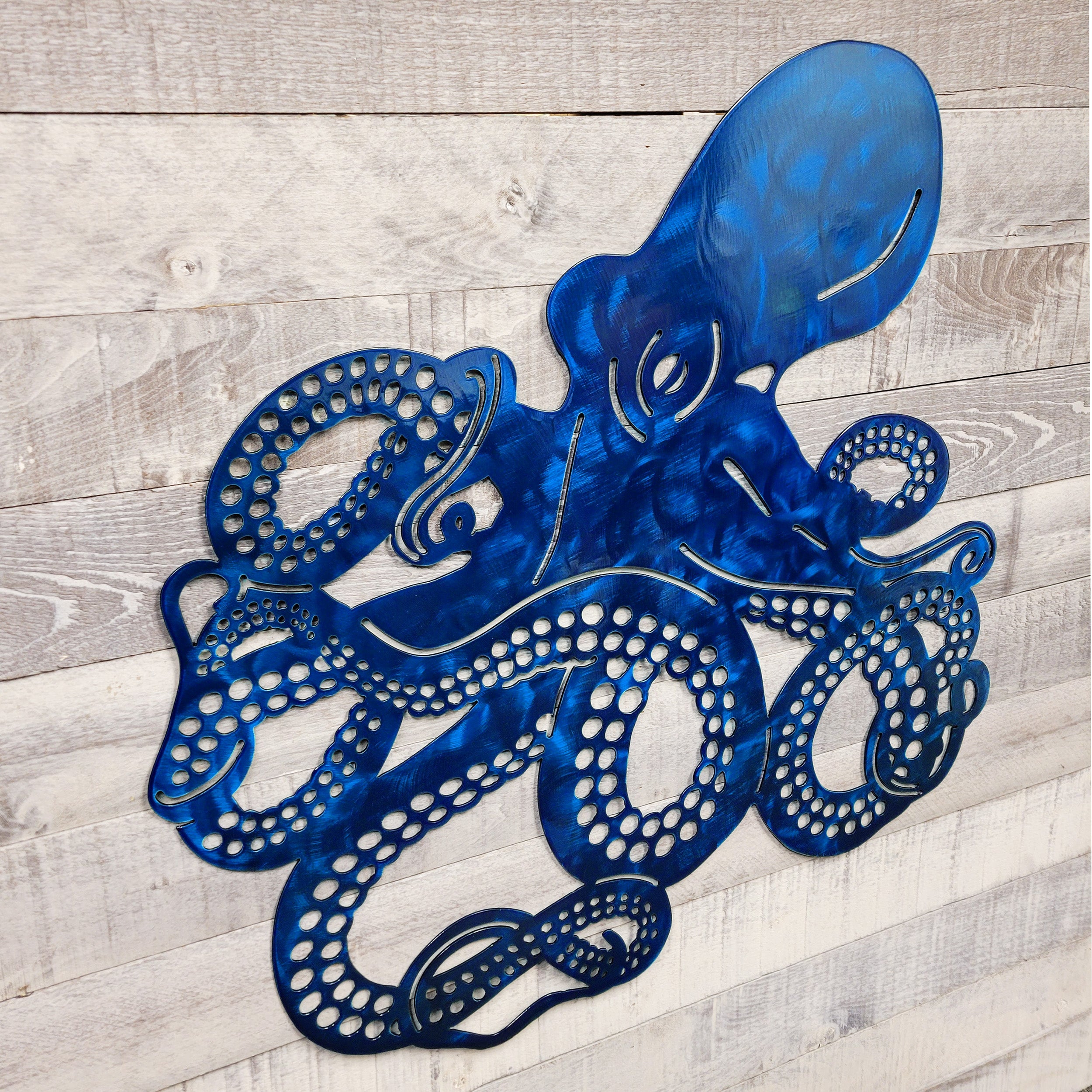 Metal wall art of a blue octopus on a wooden surface