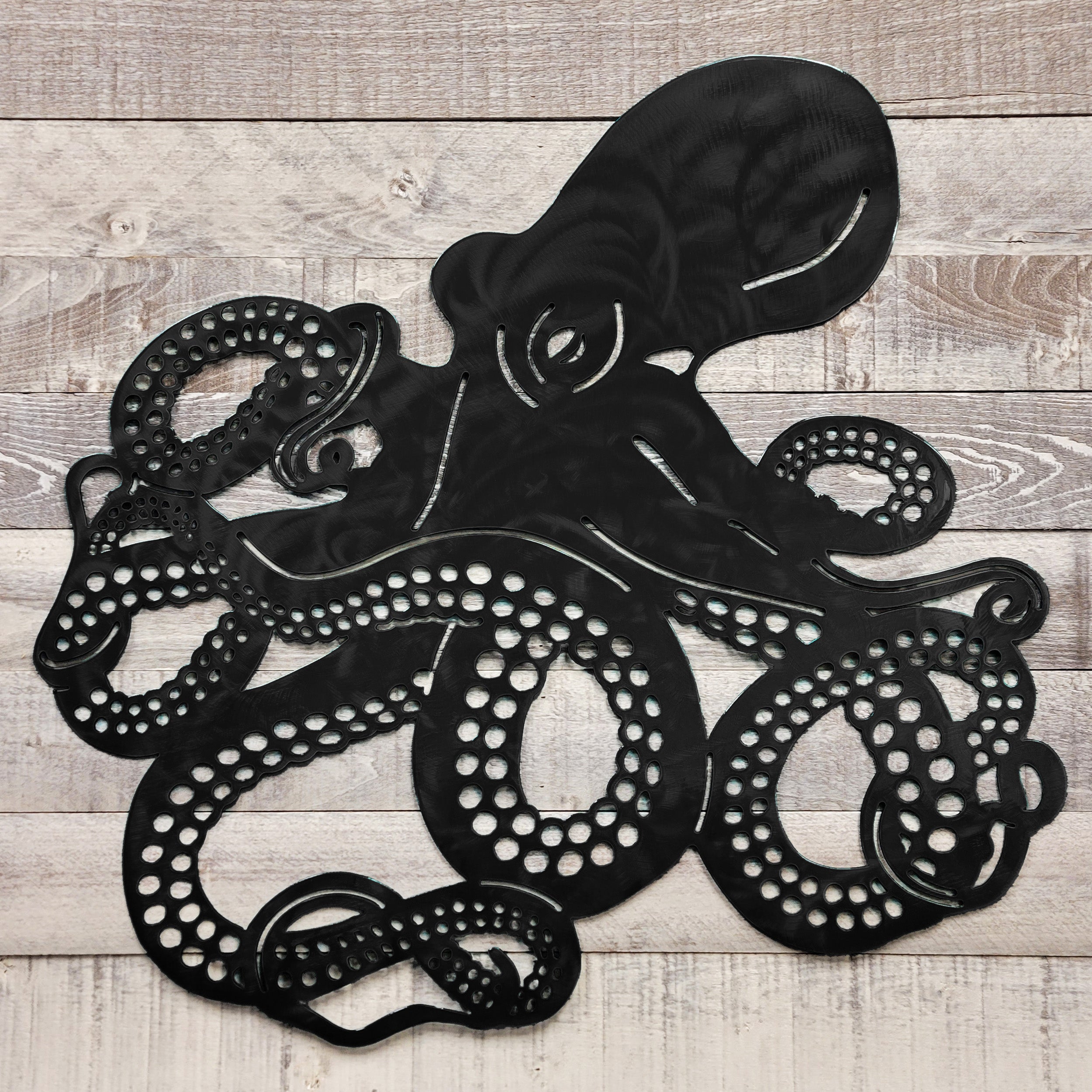 Black metal octopus wall art on a wooden surface