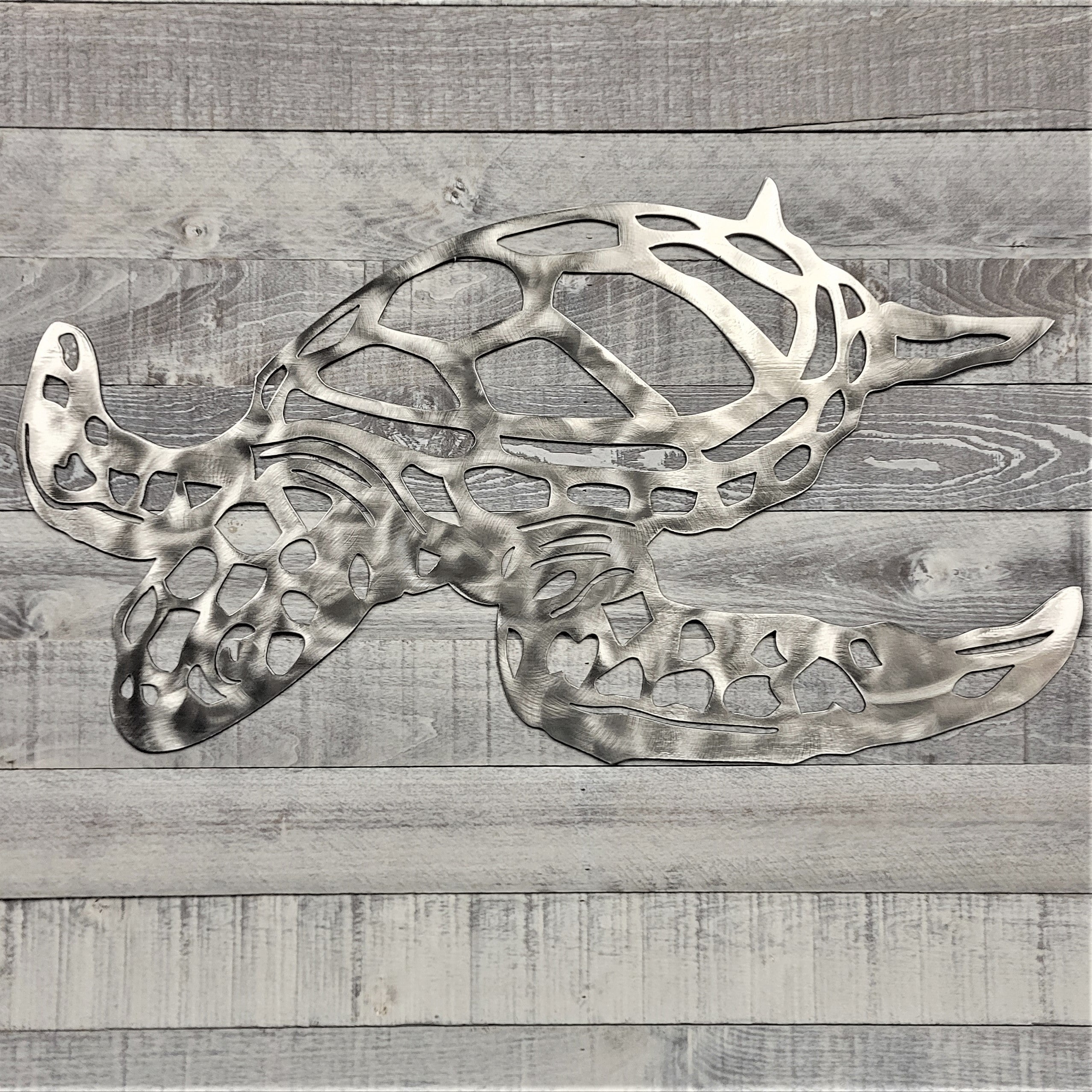 Metal wall art of a stylized turtle on a wooden background