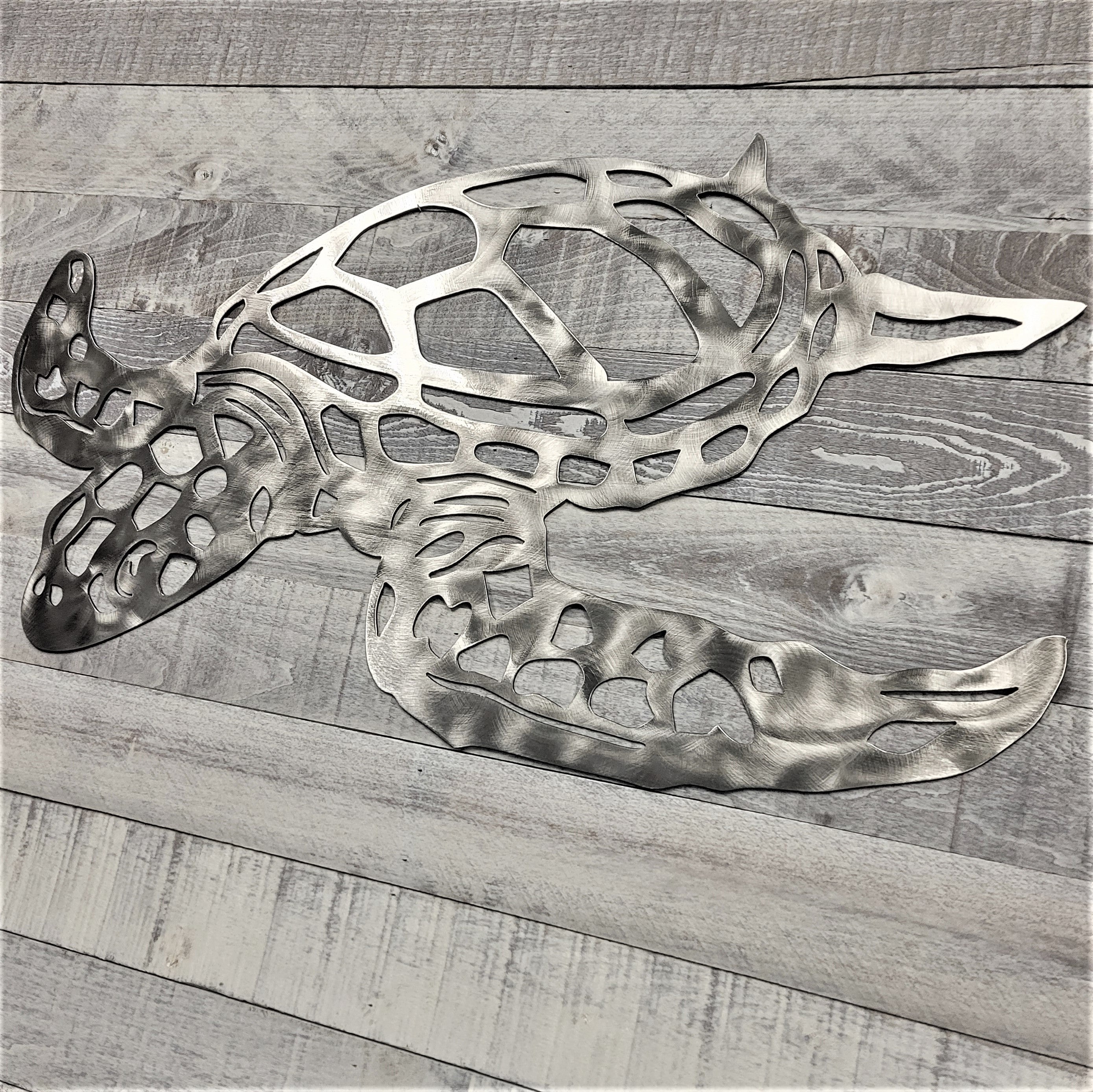 Metal turtle wall art on a wooden surface