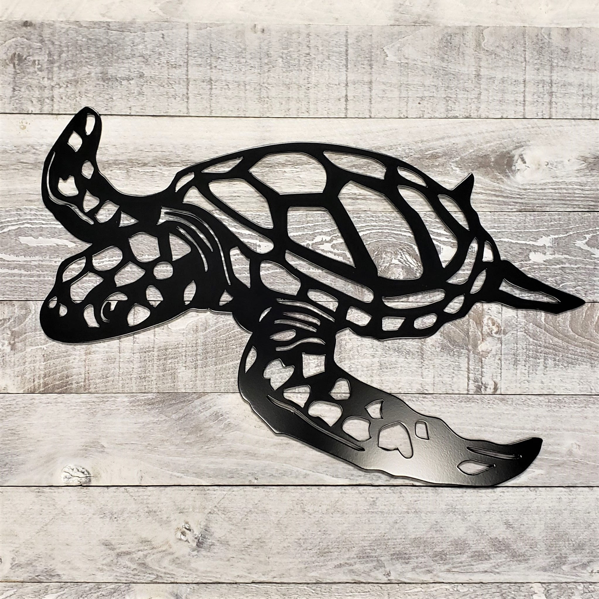 Metal turtle wall art on a wooden surface