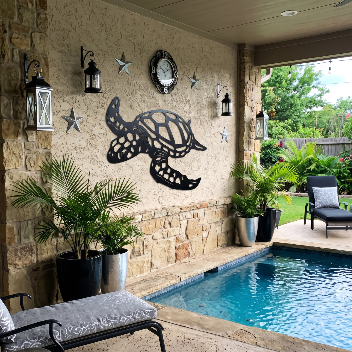 A black metal sea turtle wall decor piece mounted on a beige stucco wall in a backyard patio setting next to a swimming pool, with potted plants, lanterns, and outdoor furniture visible.
