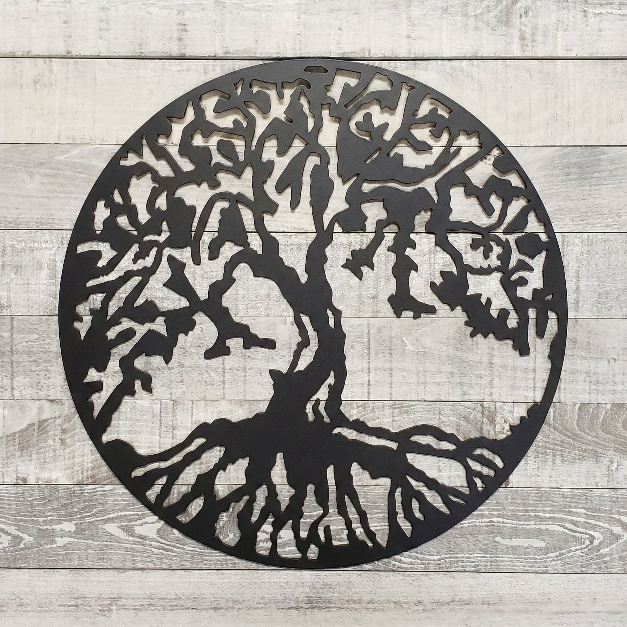 Decorative metal tree of life wall art on a wooden background
