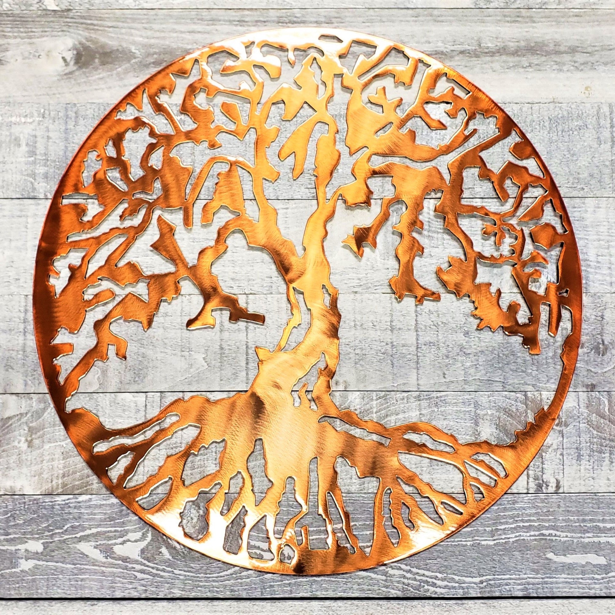 Copper-colored metal tree wall art on a wooden background
