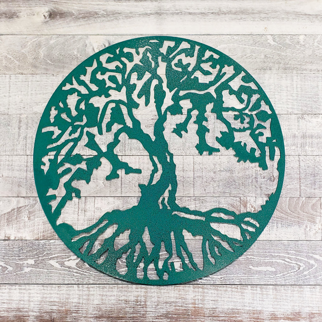 Decorative metal tree of life cutout on a wooden surface