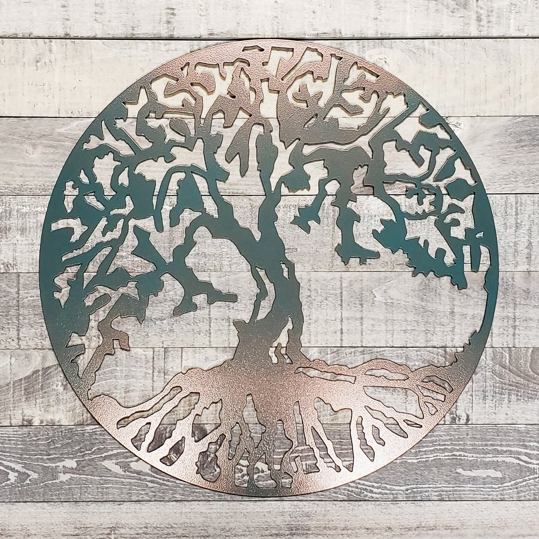 Decorative metal wall art of a tree with intricate cut-out design on a wooden background