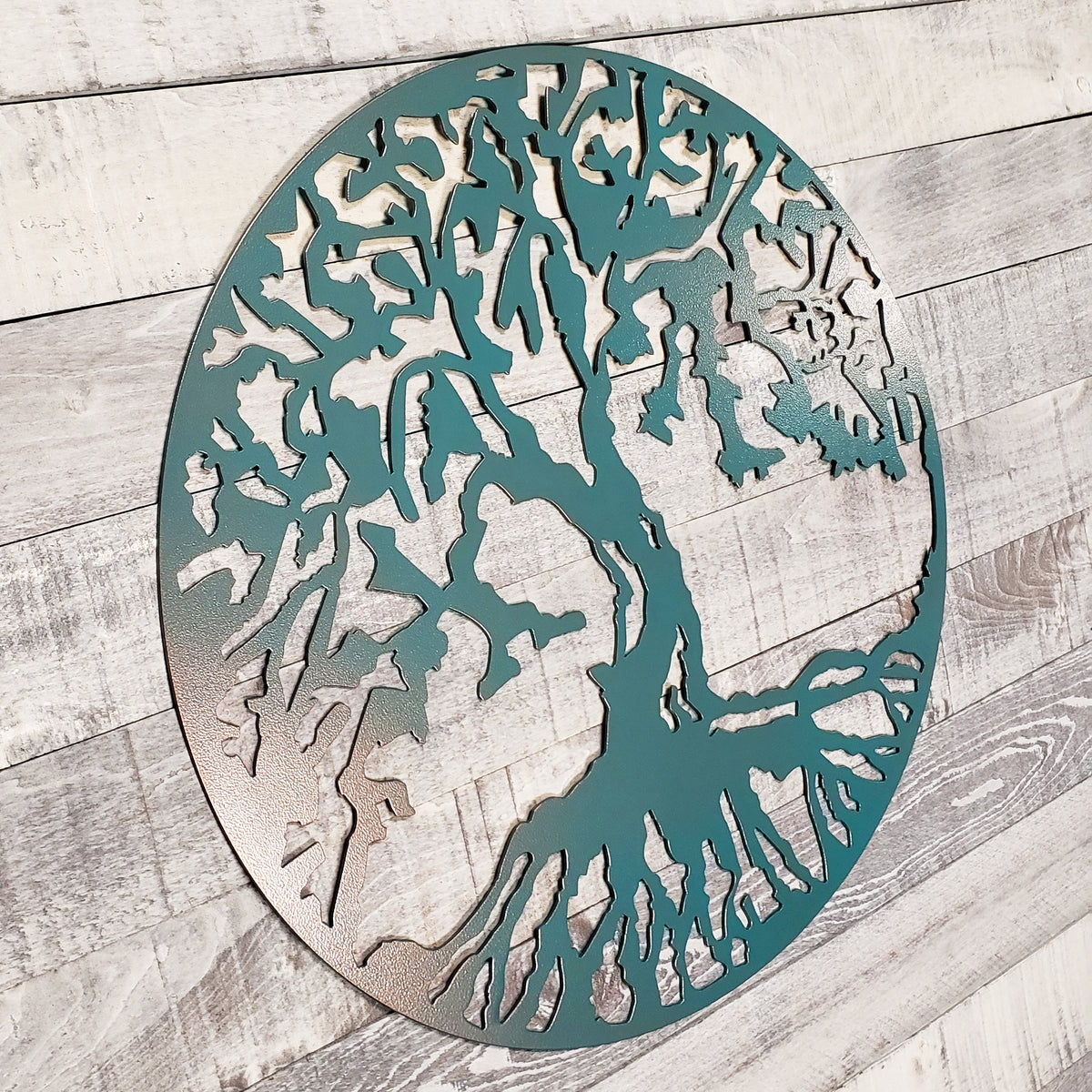 Decorative metal wall art with tree design on a wooden surface