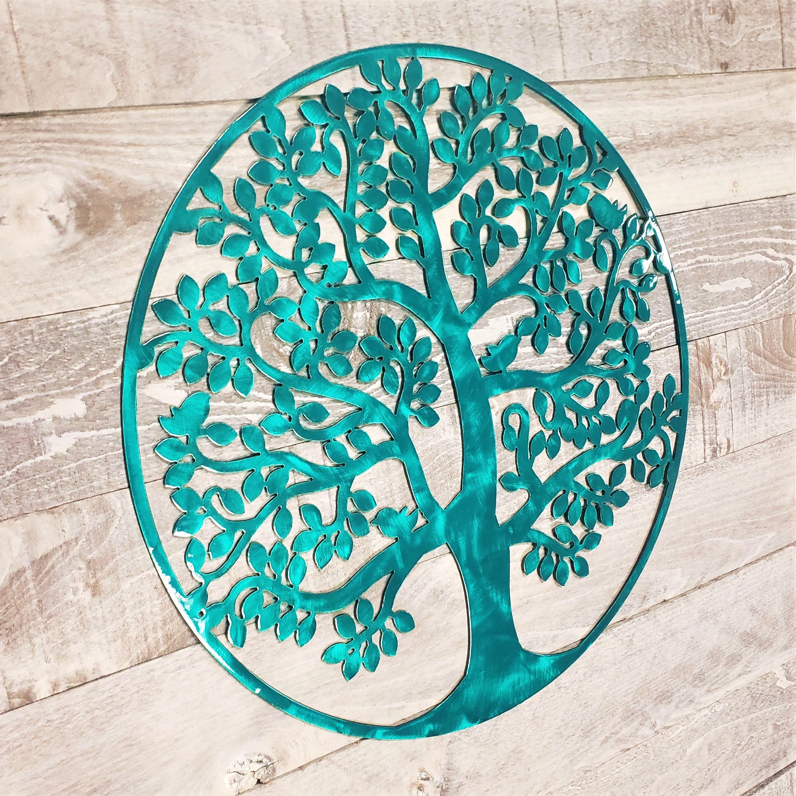 tree of life metal wall art with a brushed aqua finish on a wooden background