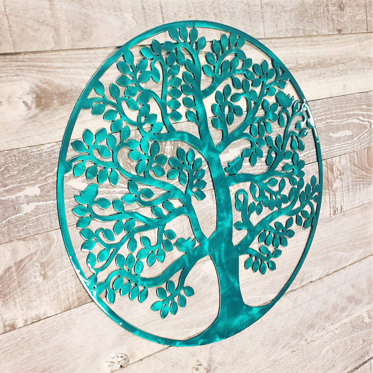 tree of life metal wall art with a brushed aqua finish on a wooden background