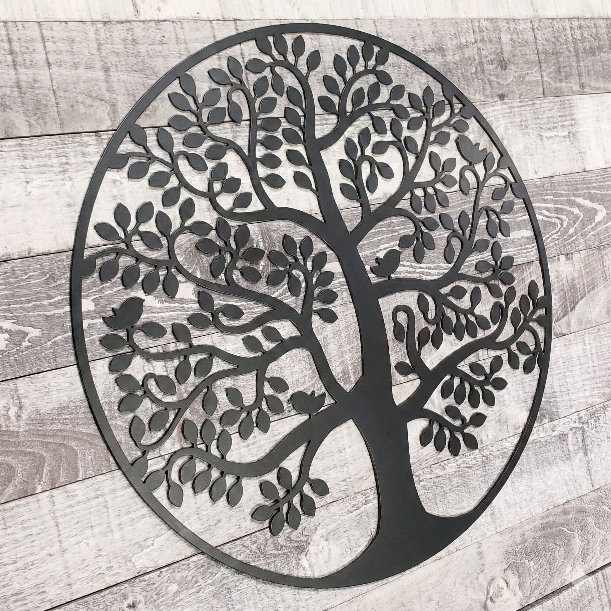 Decorative metal tree wall art on a wooden surface