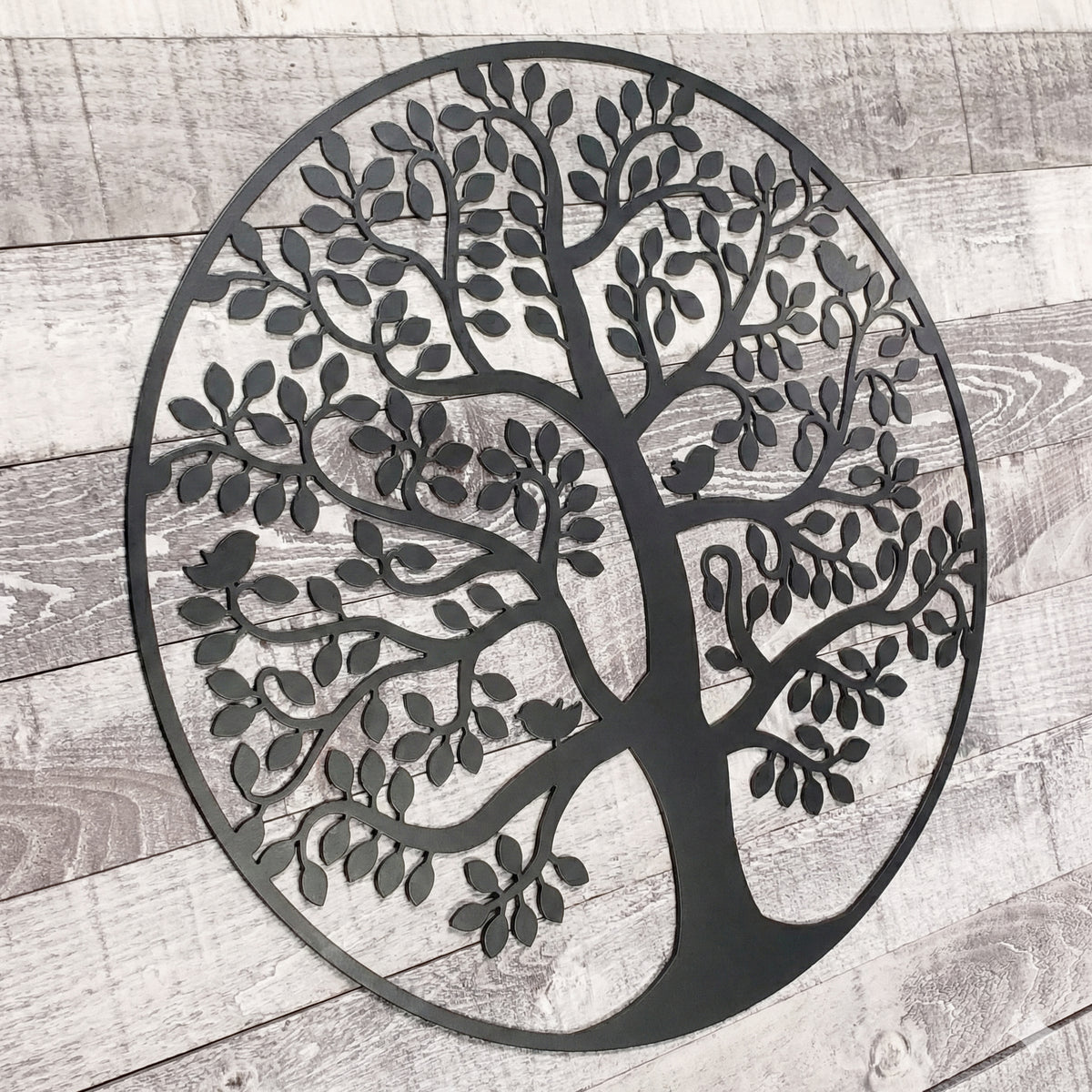 Decorative metal tree wall art on a wooden surface