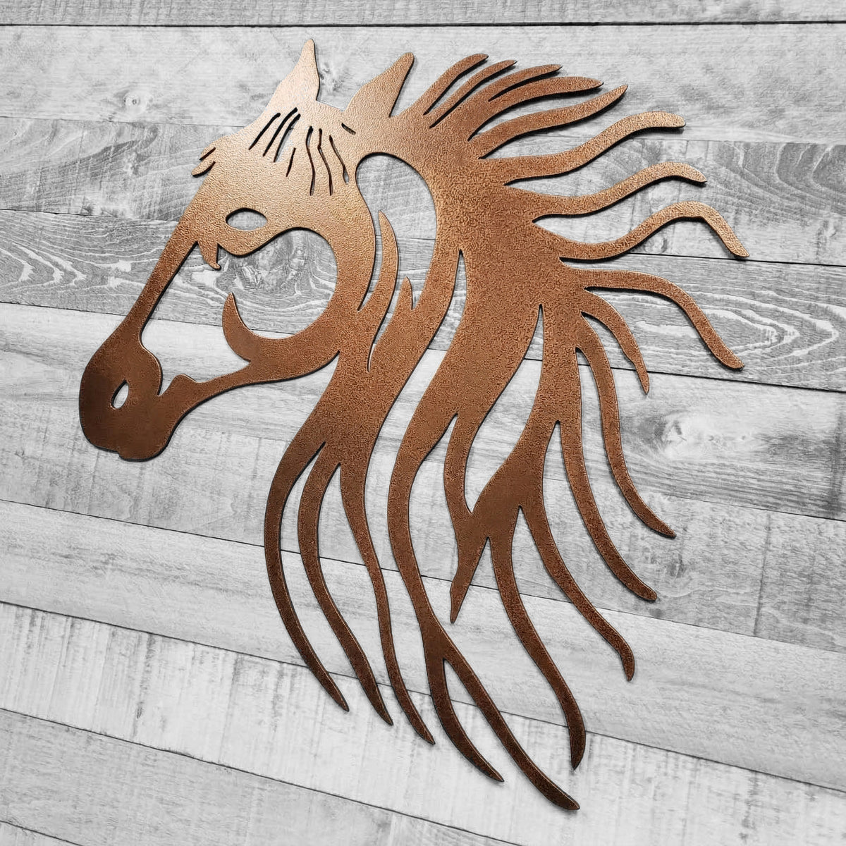 Copper-colored metal horse head wall art on a wooden background