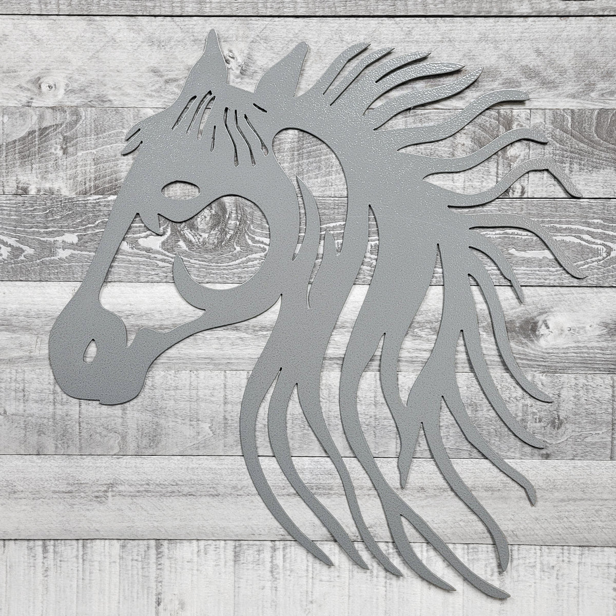 silver metal horse head wall art on a wooden background