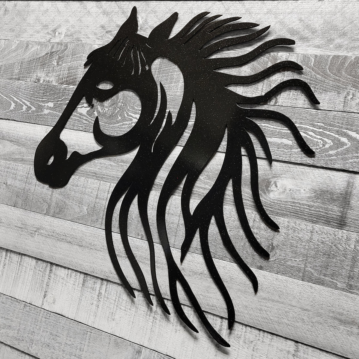 black metal horse head wall art on a wooden background