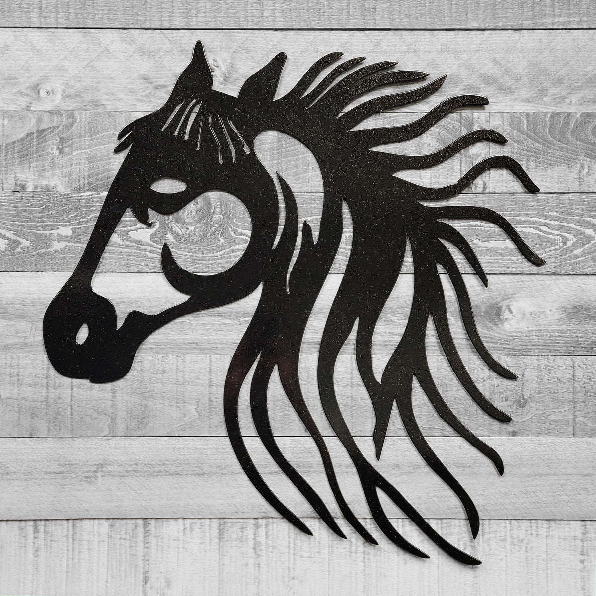 black metal horse head wall art on a wooden background