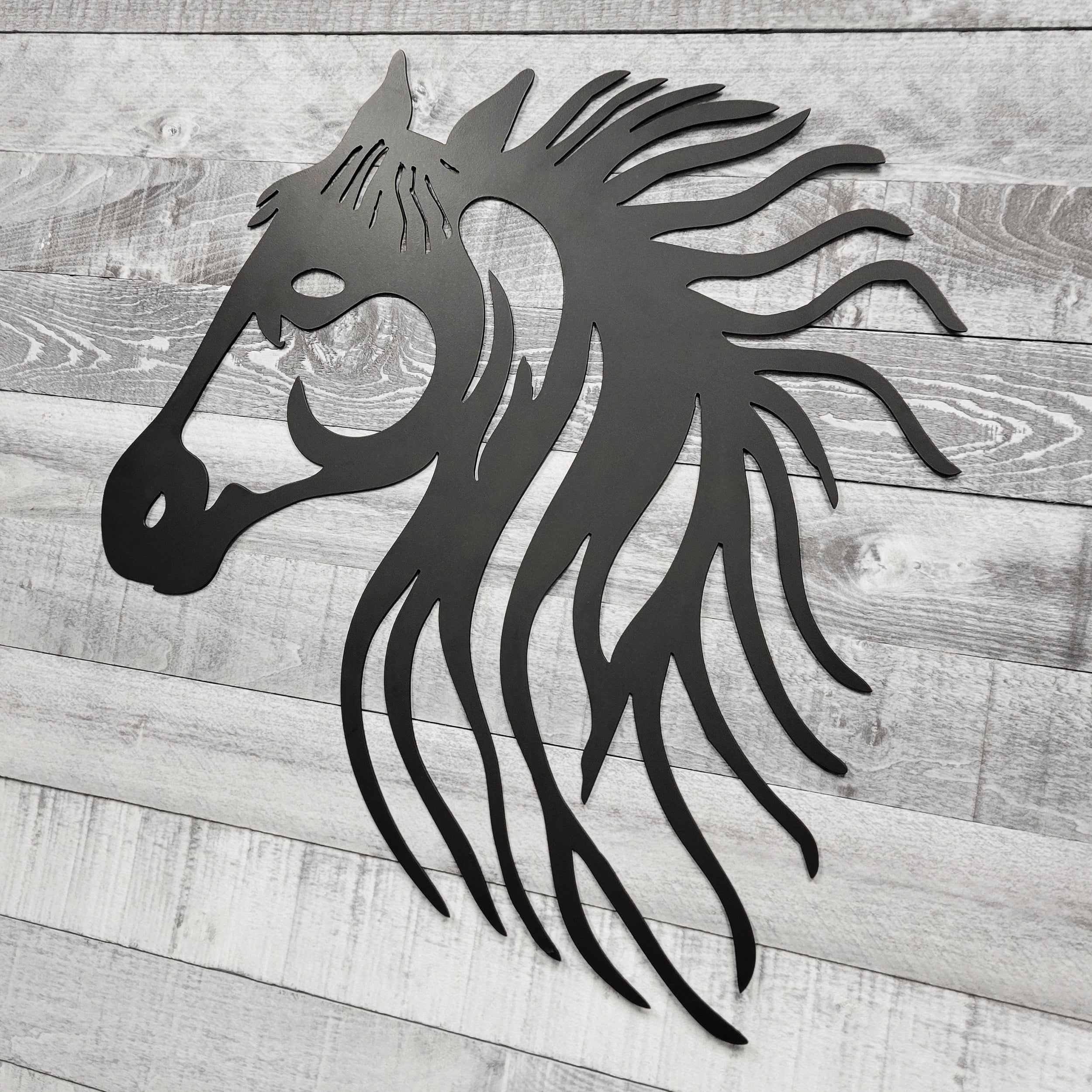 black metal horse head wall art on a wooden background