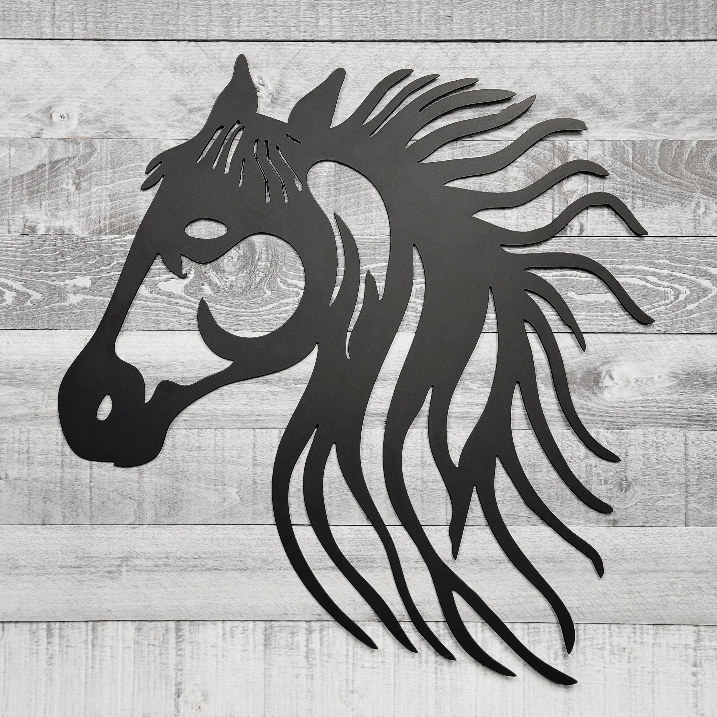 black metal horse head wall art on a wooden background