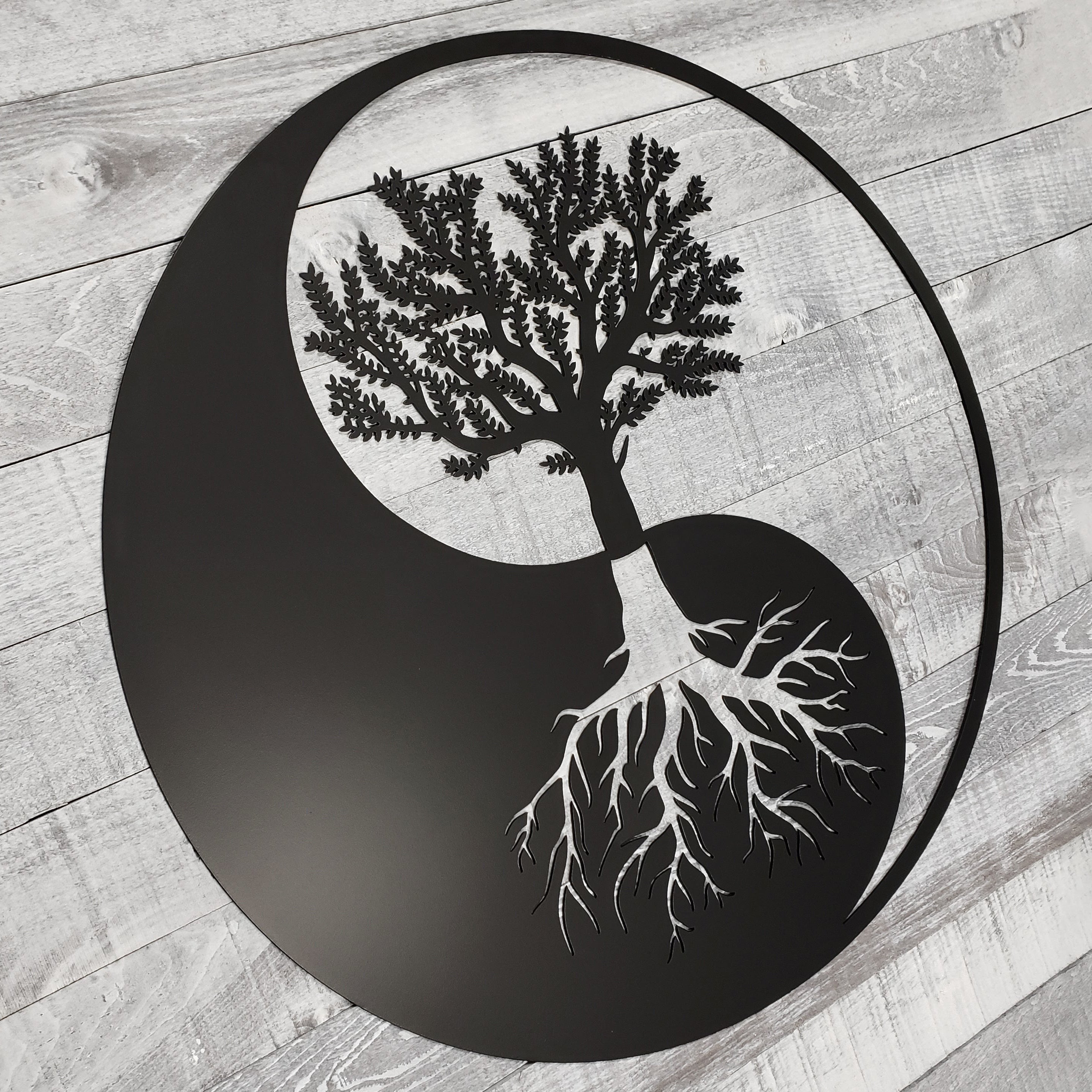 Yin yang symbol with a tree and roots on a wooden background