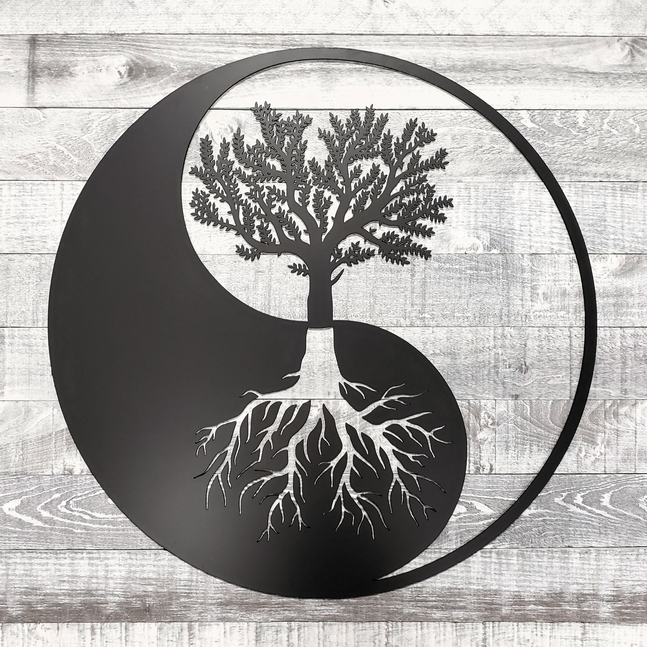 Yin yang symbol with a tree and roots on a wooden background