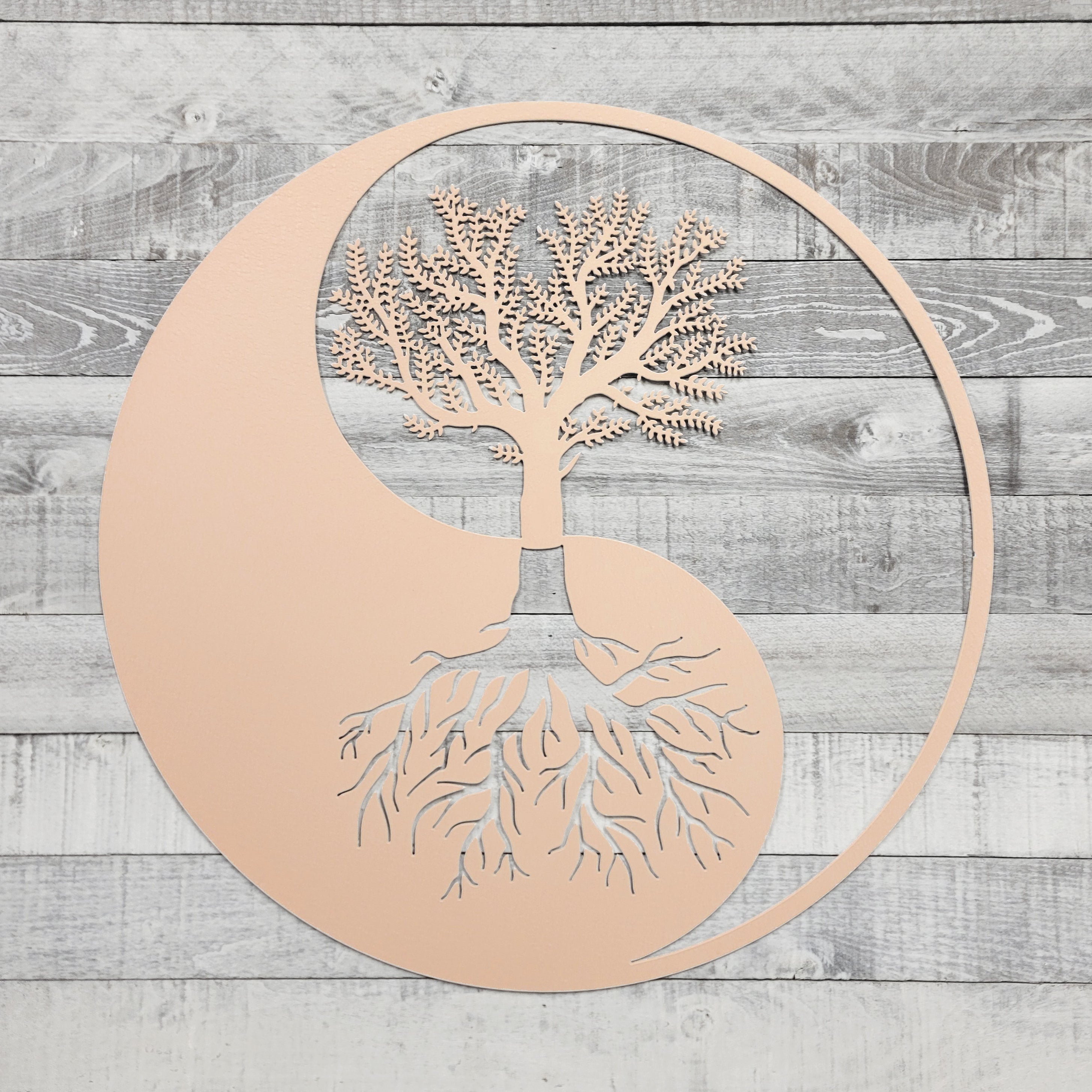 Decorative wall art with a tree design inside a yin yang symbol on a wooden background