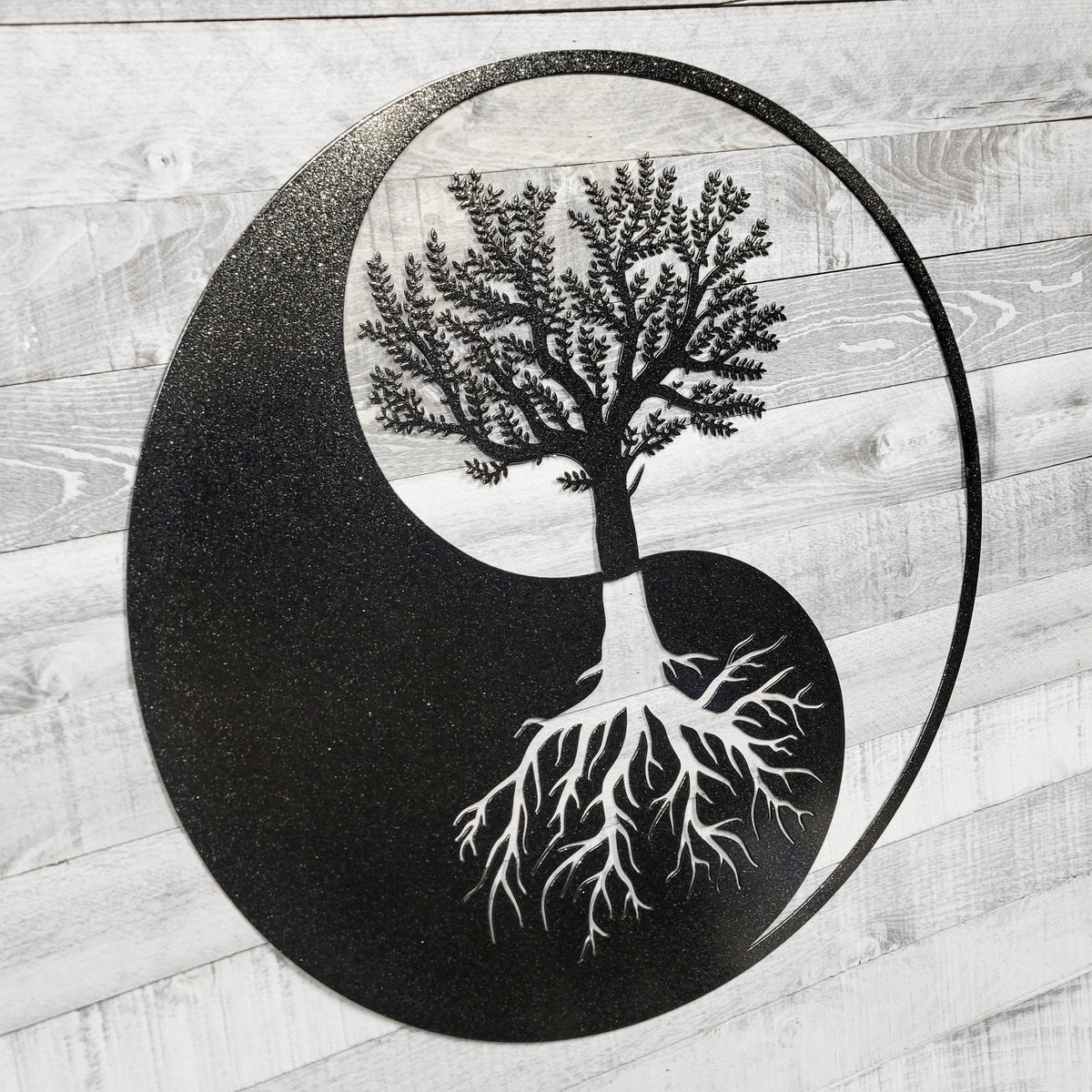 Yin yang symbol with a tree and roots on a wooden background